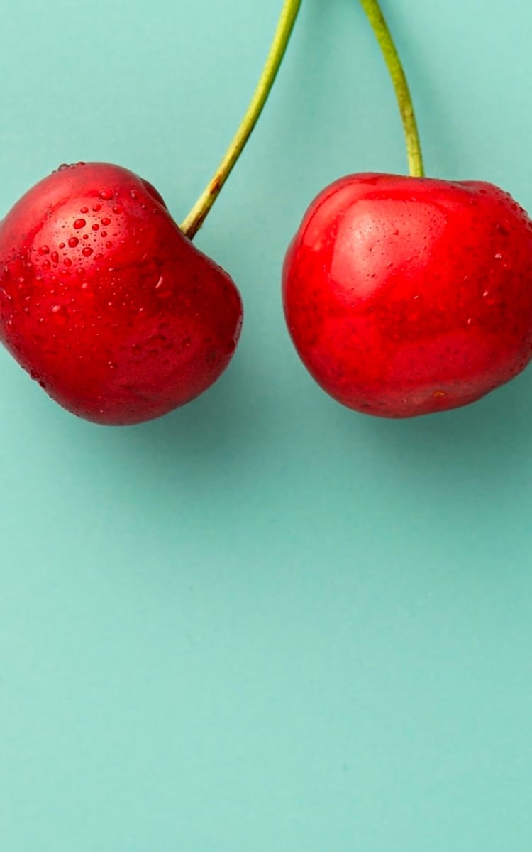 two cherries with lime green background